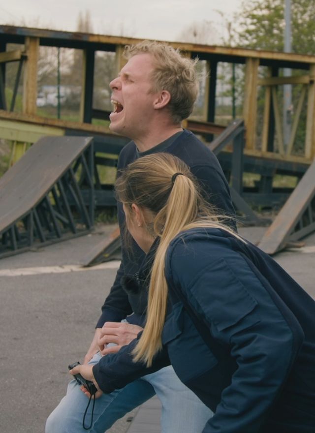 Zwei Menschen kauern erschrocken auf einer Skateanlage und schreien