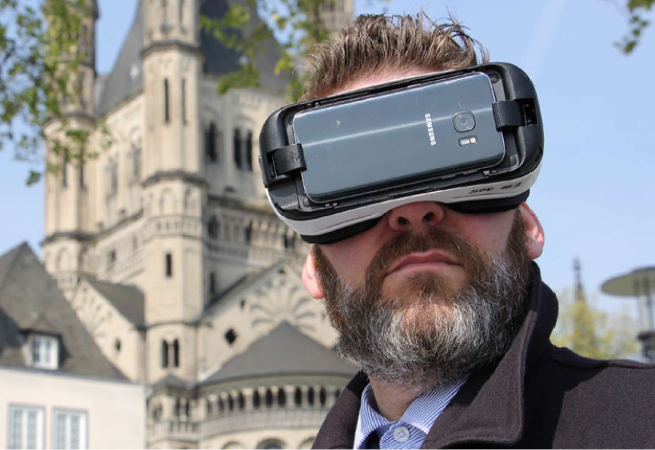 Ein Mann mit VR-Brille vor einer Kirche in der Kölner Altstadt