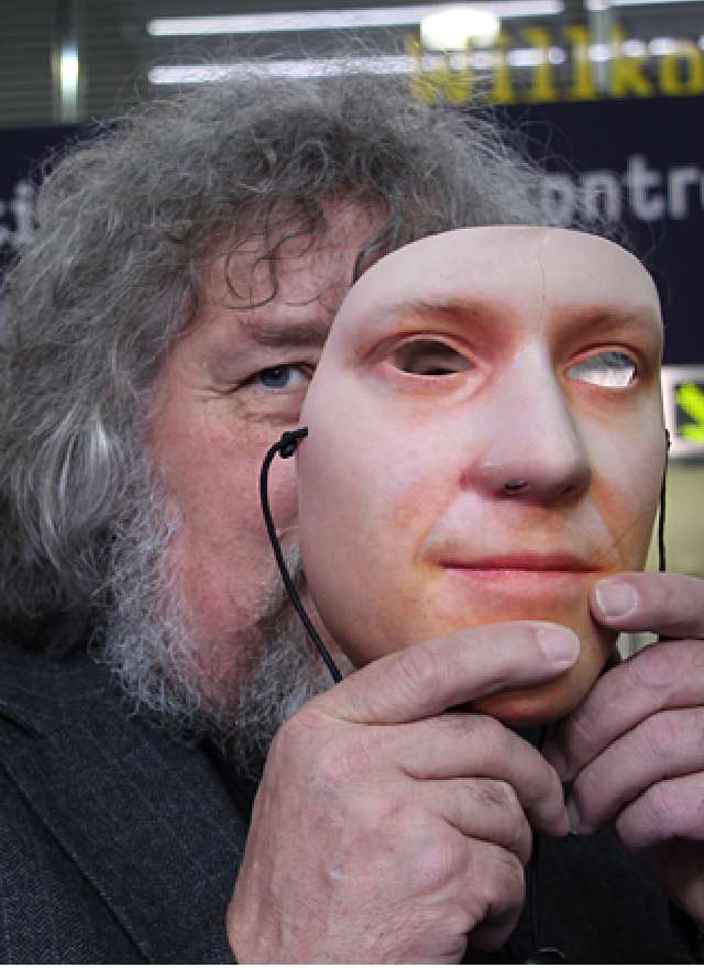 Ein Mann hält sich eine täuschend echte Gesichtsmaske vors Gesicht