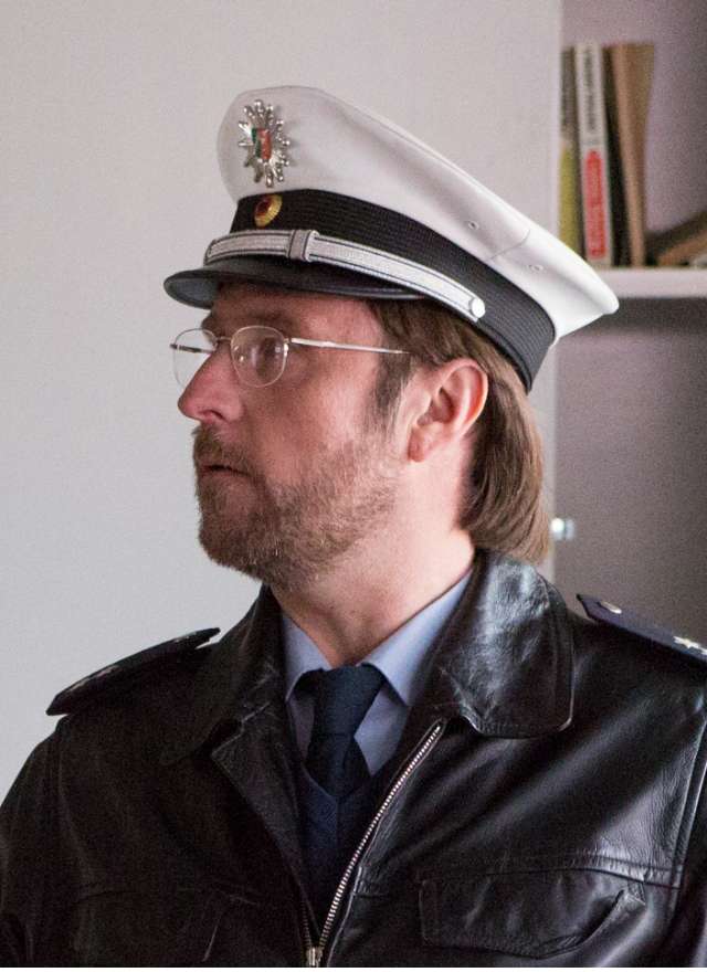 Ein Polizist mit weißer Mütze und Lederjacke im Profil