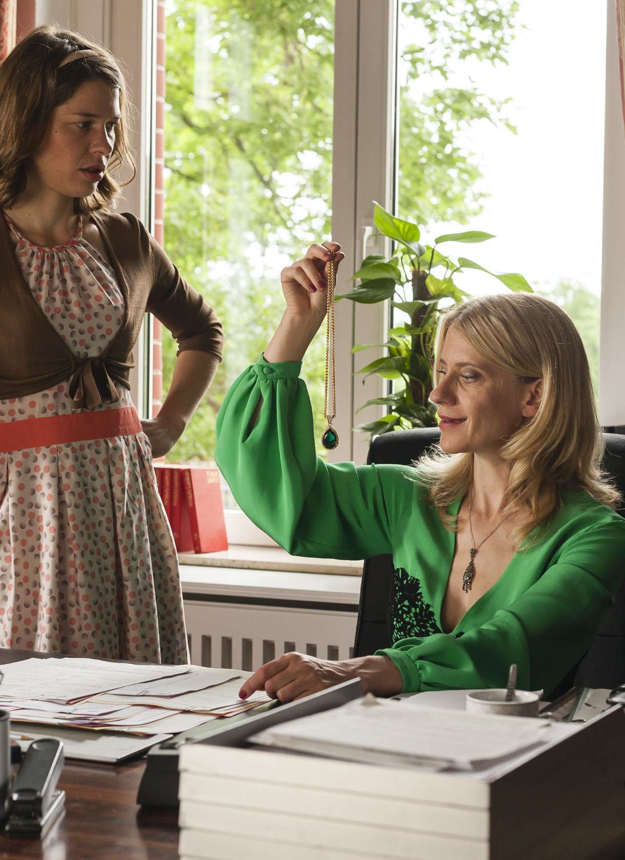 Zwei Frauen in einem hellen Büro am Fenster, eine sortiert Papierstapel