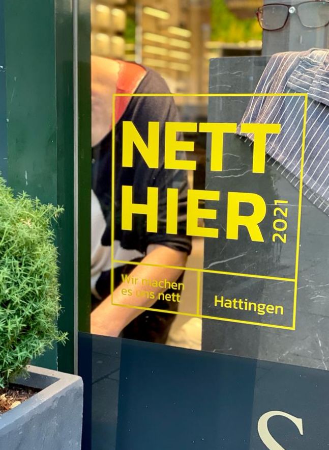 Aufkleber mit der Aufschrift "Nett hier" an einem Ladenfenster