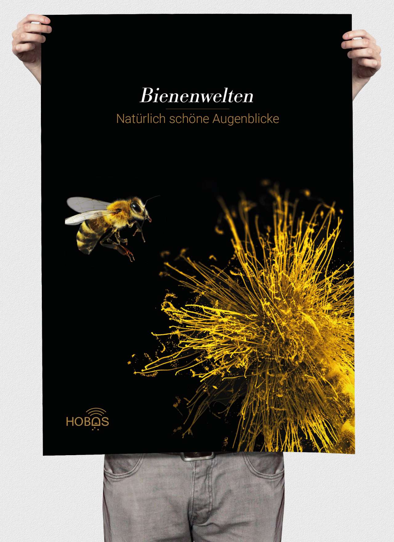 Mensch hält schwarzes Plakat mit Biene und gelber Blüte; Aufschrift: Bienenwelten. Natürlich schöne Augenblicke.