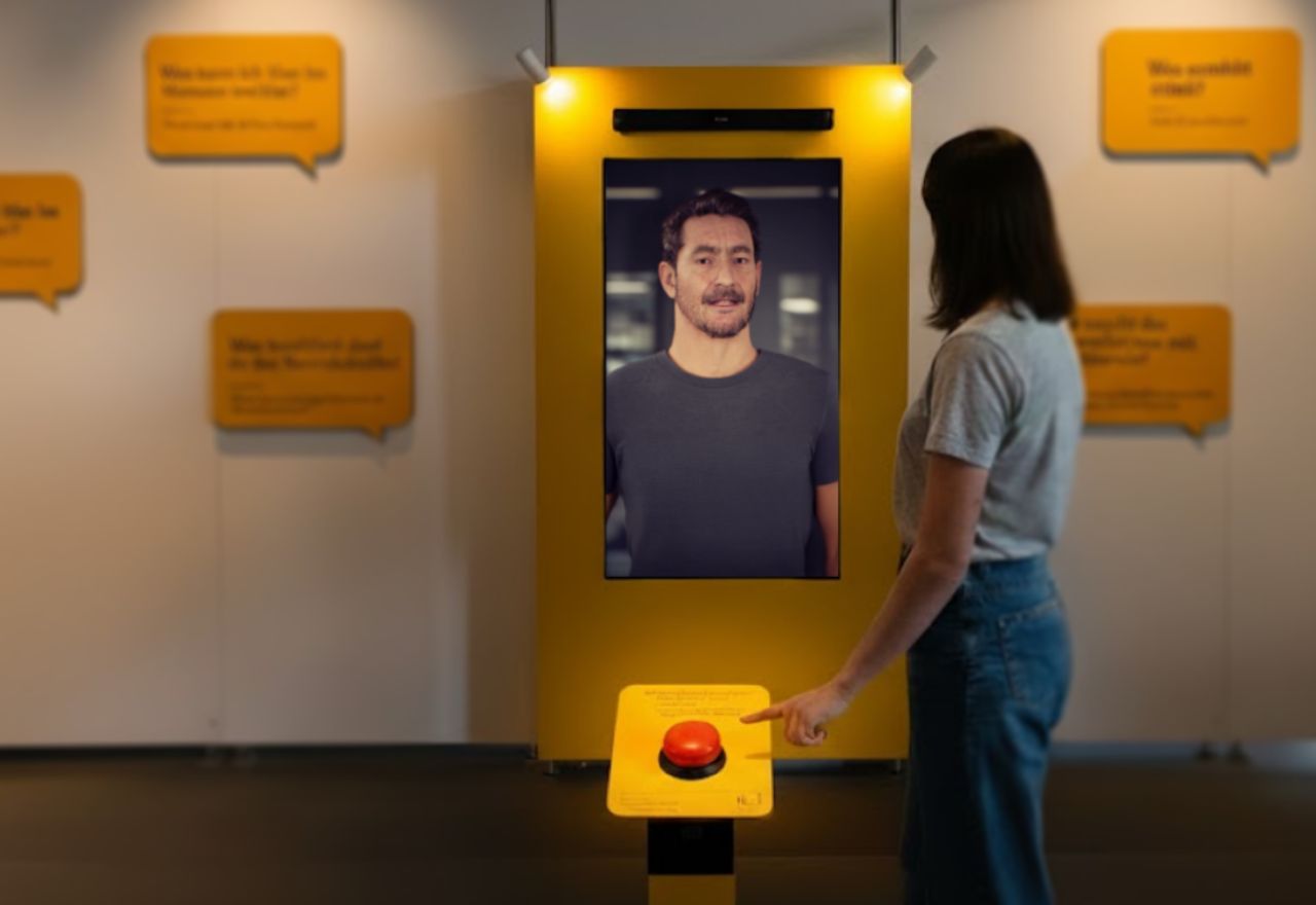 Eine Besucherin startet den Avatar über einen roten Taster an der Stele