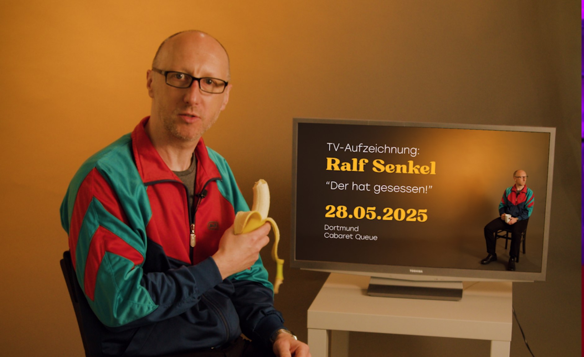 Ein Kabarettist mit Banane neben einem Fernseher mit Ankündigung der TV-Aufzeichnung