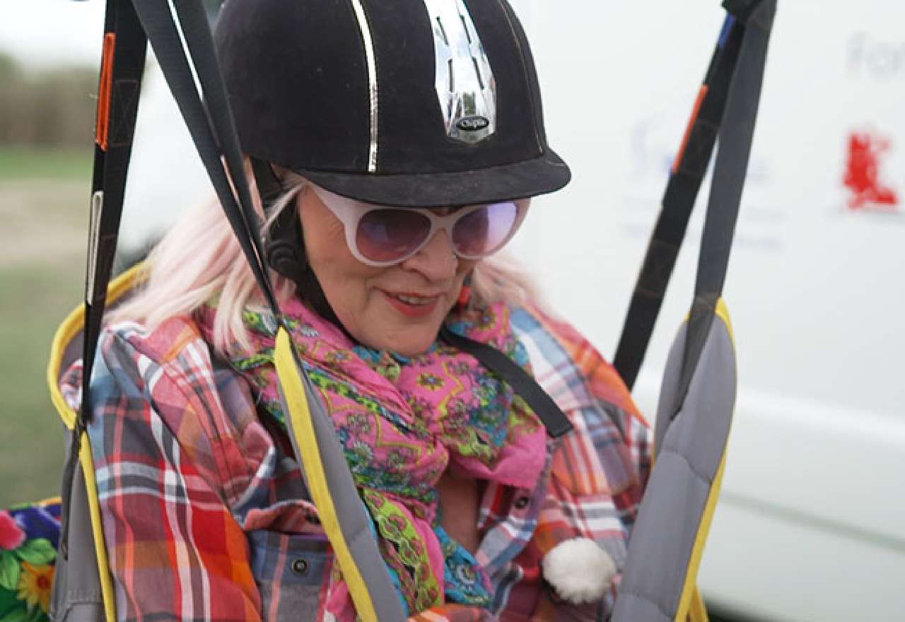 Gaby Köster wird in einem Gestell auf ein Pferd gehoben um das erste Mal zu reiten