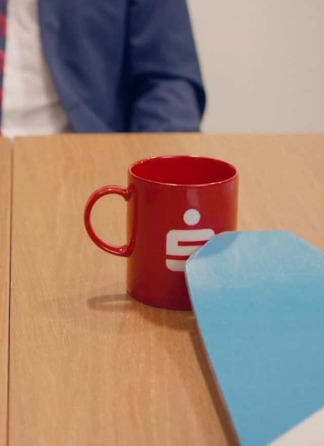 Bürotisch mit Sparkassen-Kaffeetasse und Ski